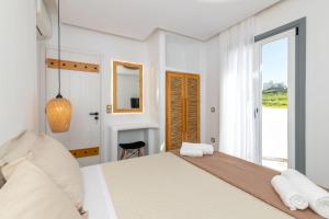 Un dormitorio blanco con una cama grande y una ventana en NAXIAN SUNSET VILLAS en Naxos