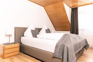 Schlafzimmer mit einem Bett mit weißer Bettwäsche und einem Fenster in der Unterkunft Ferien-Apartment im Genusshotel Hirschen (Südschwarzwald) in Kleines Wiesental