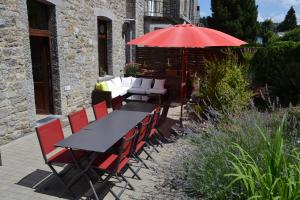 a table and chairs with an umbrella in a garden at Au Plaisir in Hastière-par-delà