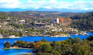 Vue aride d'un lac avec des arbres et des bâtiments dans l'établissement Château d'Esparron, à Esparron-de-Verdon