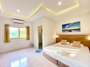 Pensiri House - SHA Extra Plus في شاطئ ناي يانغ: غرفة نوم بيضاء مع سرير كبير وحوض استحمام