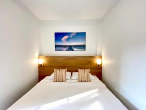 Un dormitorio con una cama blanca con una foto en la pared en Pensiri House - SHA Extra Plus en Nai Yang Beach