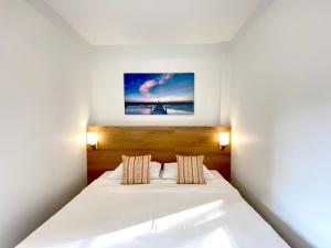 Pensiri House - SHA Extra Plus في شاطئ ناي يانغ: غرفة نوم بسرير أبيض مع صورة على الحائط