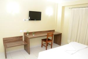 a room with a desk and a television on a wall at Requinte Hotel in Altamira