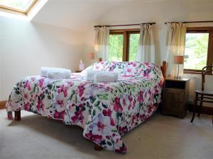 a bedroom with a large bed with a floral bedspread at The Cider Barn in Flaxley