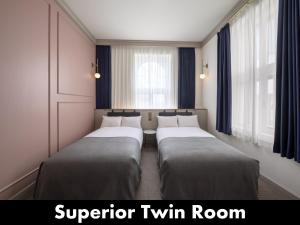 2 Betten in einem Zimmer mit Fenstern und blauen Vorhängen in der Unterkunft UNWIND HOTEL & BAR OTARU in Otaru