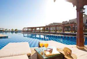 a hotel pool with two glasses of orange juice at Sunrise Arabian Beach Resort in Sharm El Sheikh