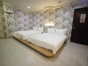 2 Betten in einem Zimmer mit einer mit Aufklebern bedeckten Wand in der Unterkunft 合悅都會商旅 Heyue HOTEL in Hsinchu