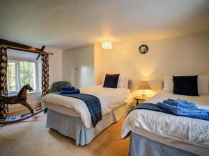 a bedroom with two beds and a chair and a window at Foley's Cottage in Warminster