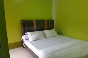 a small bedroom with a bed with green walls at OYO 3487 Es Em Je Residence in Lubukpakam