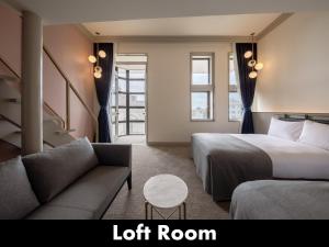 ein Hotelzimmer mit einem Bett und einem Sofa sowie einem Loft-Zimmer in der Unterkunft UNWIND HOTEL & BAR OTARU in Otaru