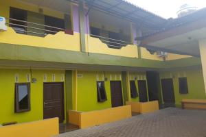 an empty building with green and yellow walls and doors at OYO 3487 Es Em Je Residence in Lubukpakam