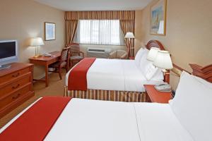 a hotel room with two beds and a desk at Rockville Centre Hotel - JFK Airport in Lynbrook +18 photos