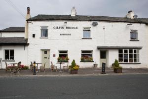 a white building with tables and chairs in front of it at Gilpin Bridge Inn in Kendal