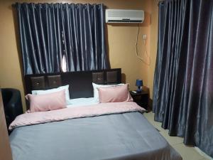 a bedroom with a bed with pink pillows at StayCation Suites And Apartment in Lagos