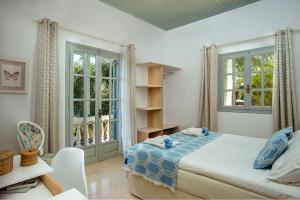 a bedroom with a bed and two windows at PaxosBlue Suites & Villas in Gaios