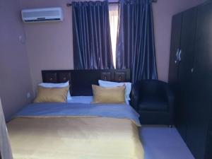 a bedroom with a bed and a chair and a window at StayCation Suites And Apartment in Lagos