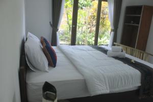 een bed met witte lakens en kussens in een slaapkamer bij Umah De Arlika UBUD in Ubud