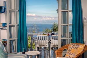 a room with a view of the ocean from a balcony at PaxosBlue Suites & Villas in Gaios