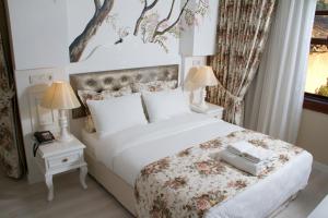 a bedroom with a large white bed with flowers on it at Kaleiçi Ozkavak Hotel in Antalya