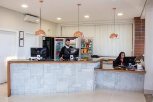 two people are sitting at a counter in a pharmacy at Portal Hotel Mogi Mirim in Mogi Mirim