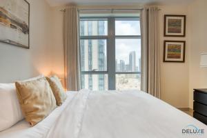 um quarto com uma cama branca e uma grande janela em Neat 1BR at Claren Tower 1 Downtown Dubai by Deluxe Holiday Homes em Dubai
