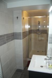 uma casa de banho com um chuveiro e um lavatório branco em Gîte les Hortensias em Boulleret
