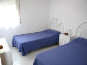2 camas en una habitación blanca con sábanas azules en Sol Pins II - Moreno, en Tamariu