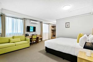 Habitación de hotel con cama y sofá amarillo en Quality Inn Sunshine Haberfield, en Sídney