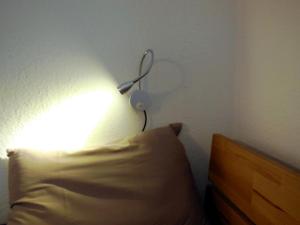 a lamp on a wall next to a bed with a pillow at Ferienzimmer Gersprenztal in Reichelsheim +4 photos