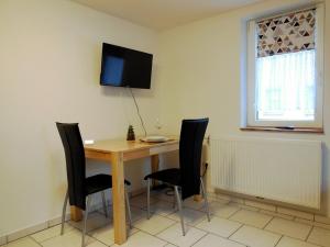 a dining room table with chairs and a television on the wall at Ferienzimmer Gersprenztal in Reichelsheim