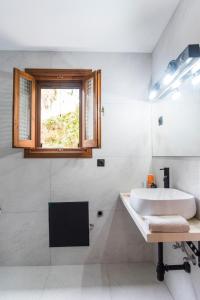 a white bathroom with a sink and a window at Villa Philippos in Vitalades