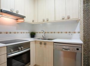 cocina con armarios blancos, fregadero y lavavajillas en GAUDI Barcelonastuff Apartments, en Barcelona