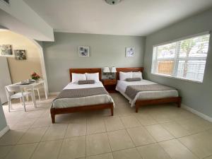 a bedroom with two beds and a table and a window at Coral Key Inn in Fort Lauderdale