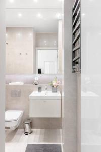 a white bathroom with a sink and a toilet at Luxury Apartment 60 in Warsaw