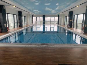 a swimming pool in a building with windows at A Cosy Apartment in Vinhomes Green Bay Ha Noi in Hanoi