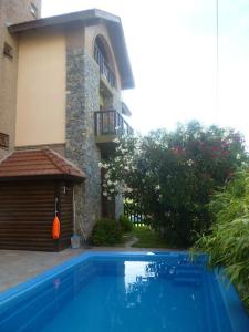 a blue swimming pool in front of a house at Acquamarina Hotel in Villa Gesell