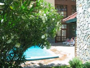 a pool in a yard with people sitting on a patio at Acquamarina Hotel in Villa Gesell