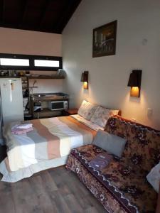 ein Schlafzimmer mit einem Bett und einem Sofa darin in der Unterkunft Jardins de Canela - Aptos e Casas Bairro Nobre em Canela in Canela