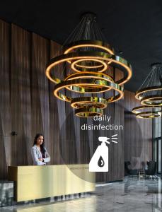 a woman standing at a counter under a large chandelier at Mennica Residence in Warsaw