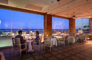 people sitting at tables in a restaurant with a view at Sunrise Arabian Beach Resort in Sharm El Sheikh