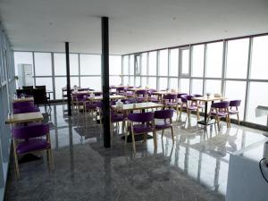 a restaurant with tables and purple chairs and windows at Lavande Hotel Beijing Changping Government Street in Beijing