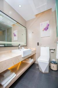 a bathroom with a sink and a toilet and a mirror at Lavande Hotels·Dalian Xinghai Park in Dalian