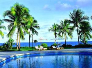 a swimming pool with palm trees and chairs and the ocean at Lavande Hotels·Sanya Pedestrian Street in Sanya