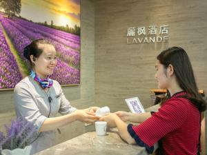 a woman sitting at a table talking to a customer at Lavande Hotels·Guangzhou East Railway Station in Guangzhou