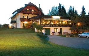 ein großes Haus mit einem davor geparkt in der Unterkunft Kraners Alpenhof BIO Bed and Breakfast Pension in Weissensee