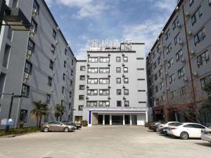 a large white building with cars parked in a parking lot at Lavande Hotel Shanghai Huamu in Shanghai