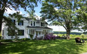 a white house with a lawn and trees at Enfield Manor Bed&Breakfast and Vacation Rental in Newfield