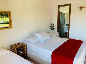 1 dormitorio con 2 camas blancas y espejo en Pousada Perola da Barra, en Barra Grande
