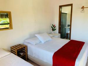 a bedroom with two white beds and a mirror at Pousada Perola da Barra in Barra Grande